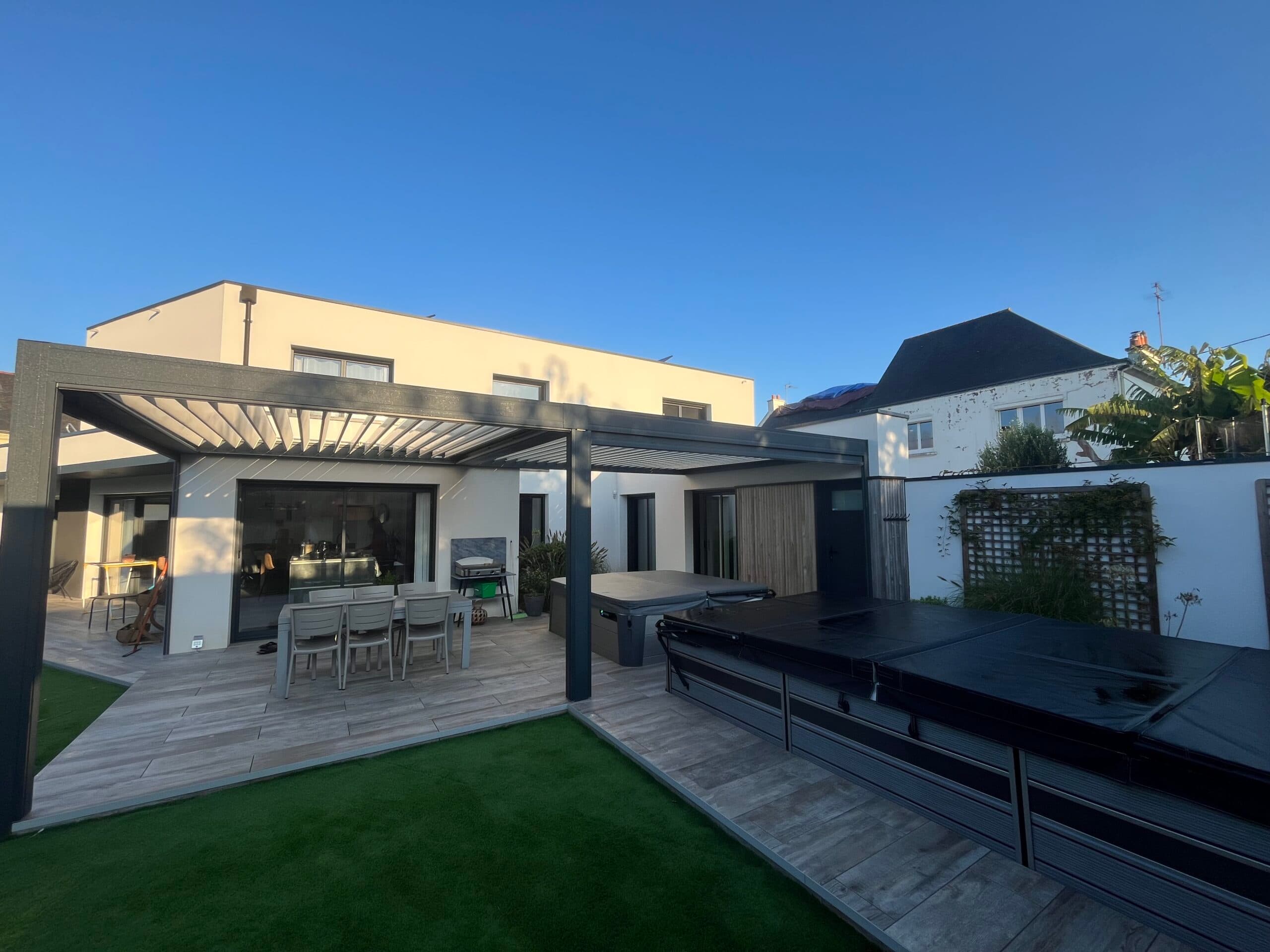 Jardin moderne avec pergola bioclimatique, terrasse carrelée et spa installé par AJY Maçonnerie.