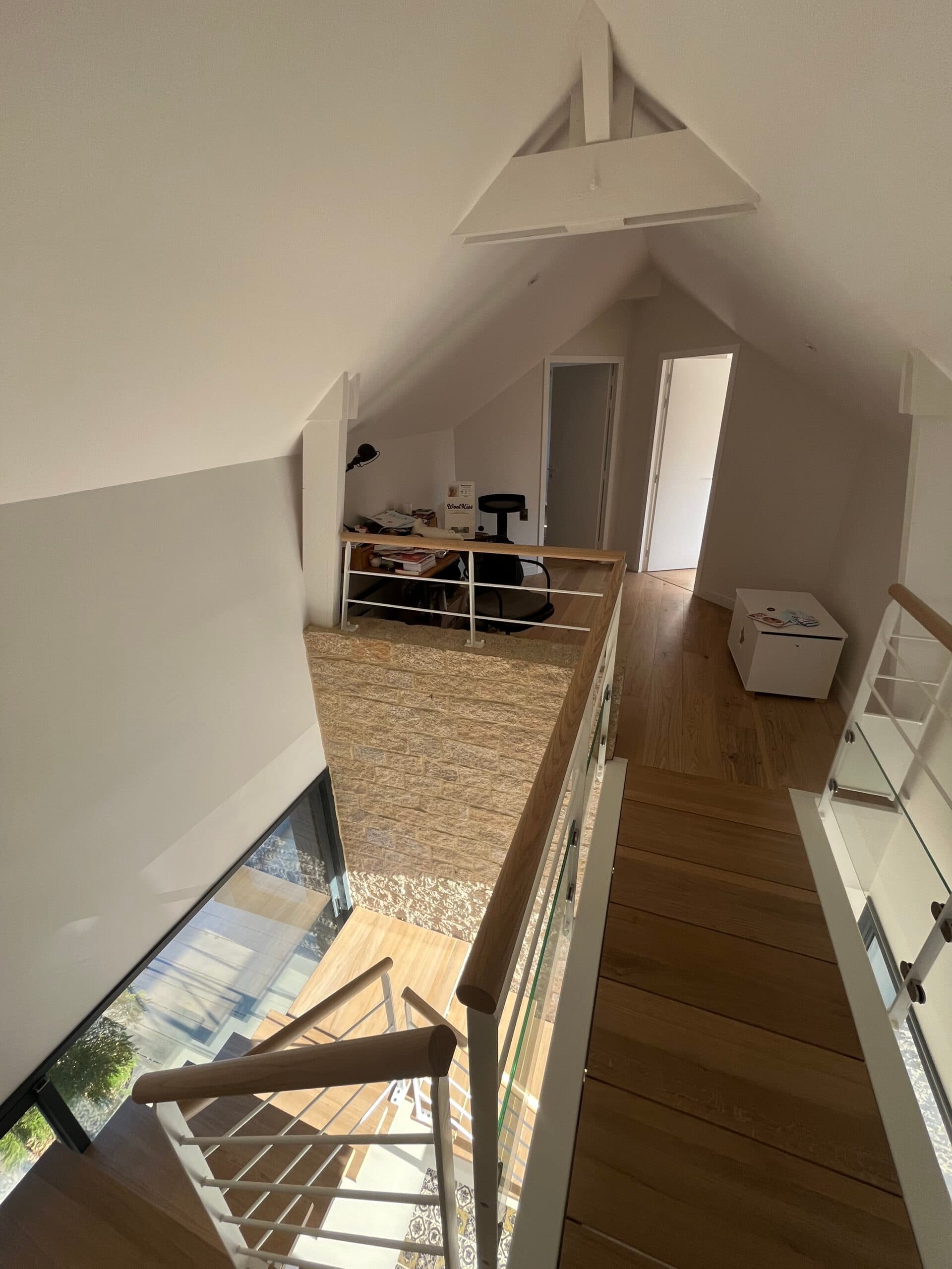 Construction neuve mixant enduit blanc et soubassement en pierre, réalisée par AJY Maçonnerie avec grands vitrages sur jardin.