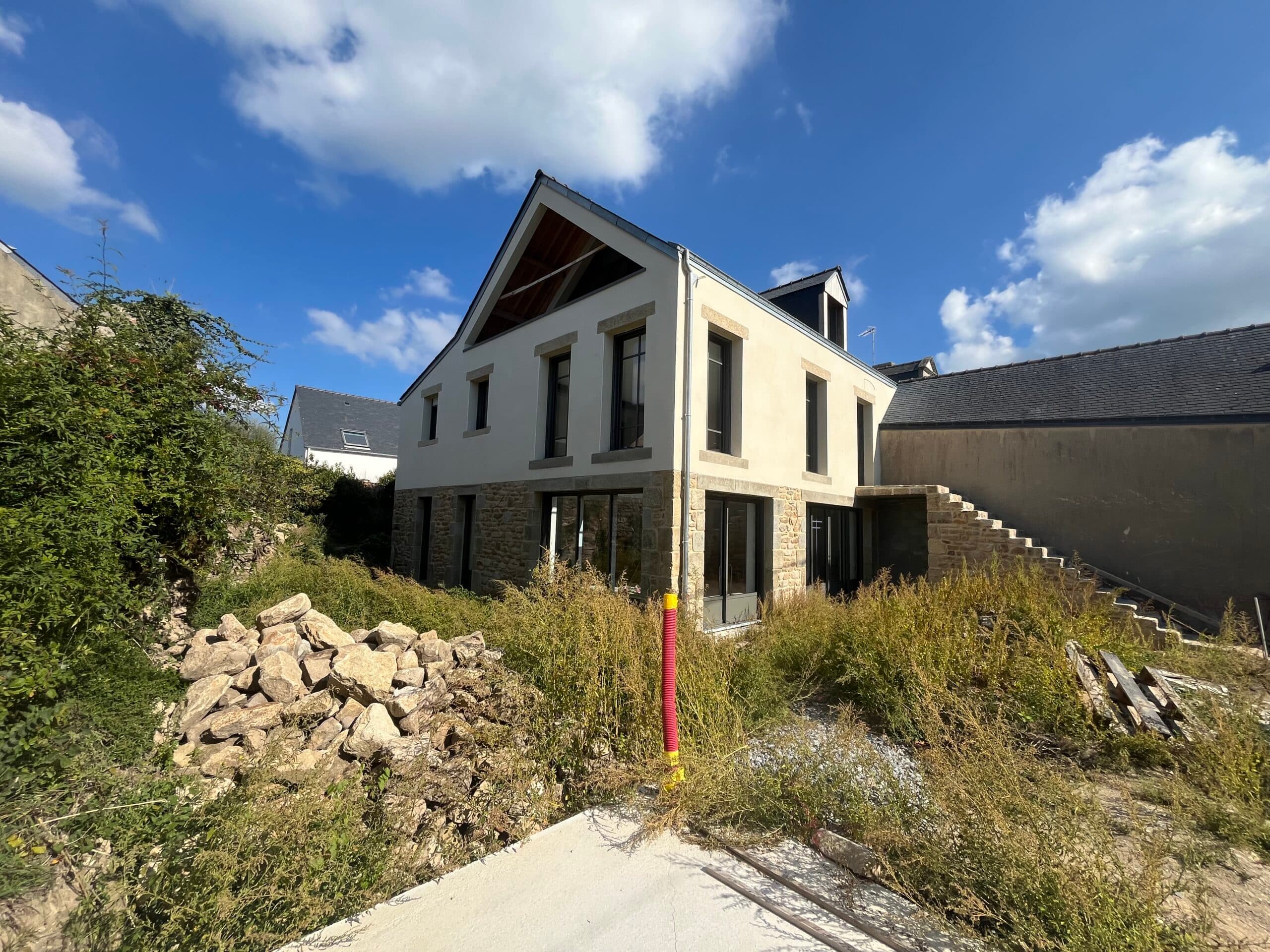 Détail d’extension en bardage bois et mur en pierre avec escalier intérieur vitré, réalisation moderne AJY Maçonnerie.