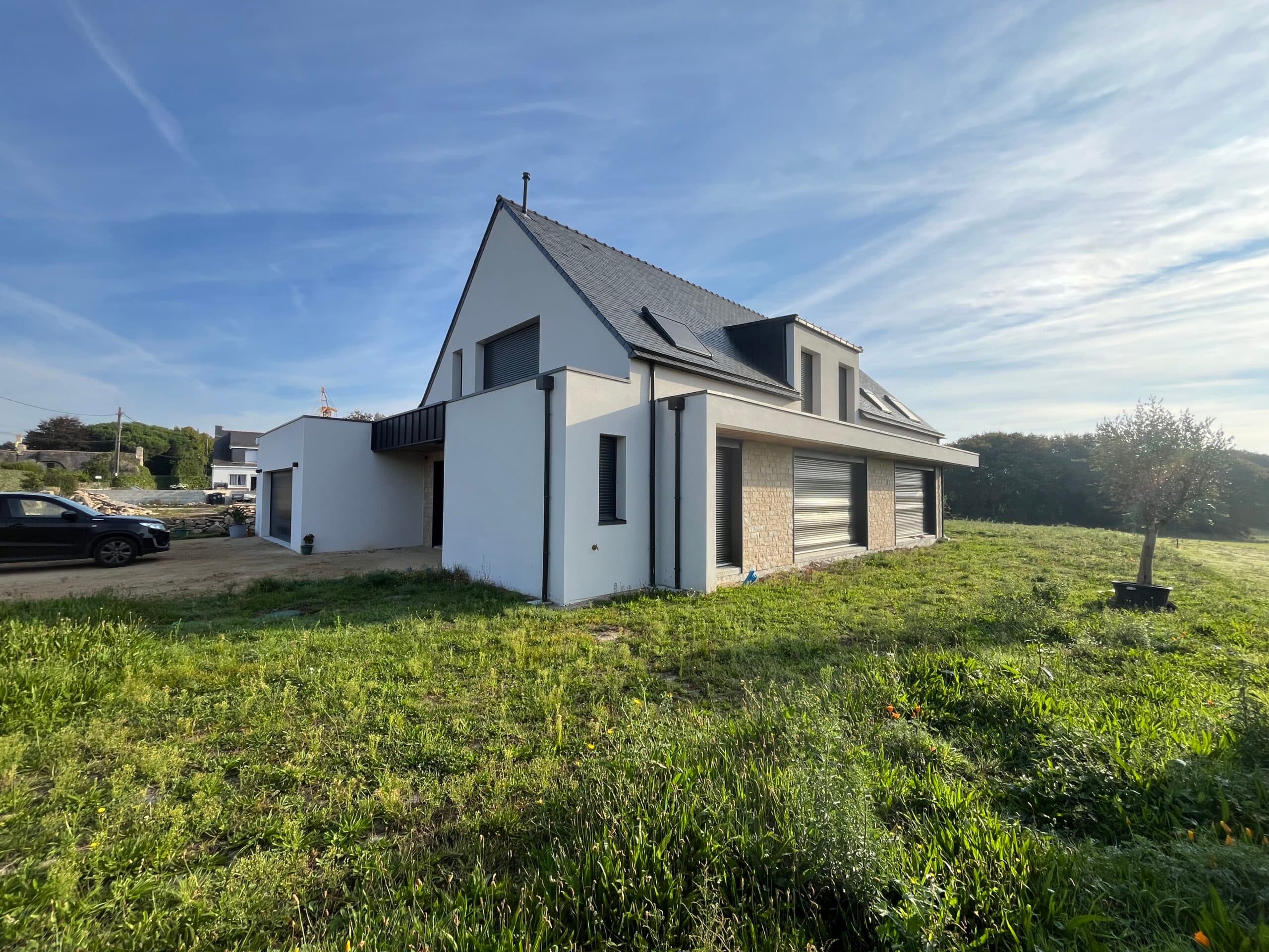 Façade arrière de maison moderne réalisée par AJY Maçonnerie avec grandes ouvertures, volets roulants et parement pierre.