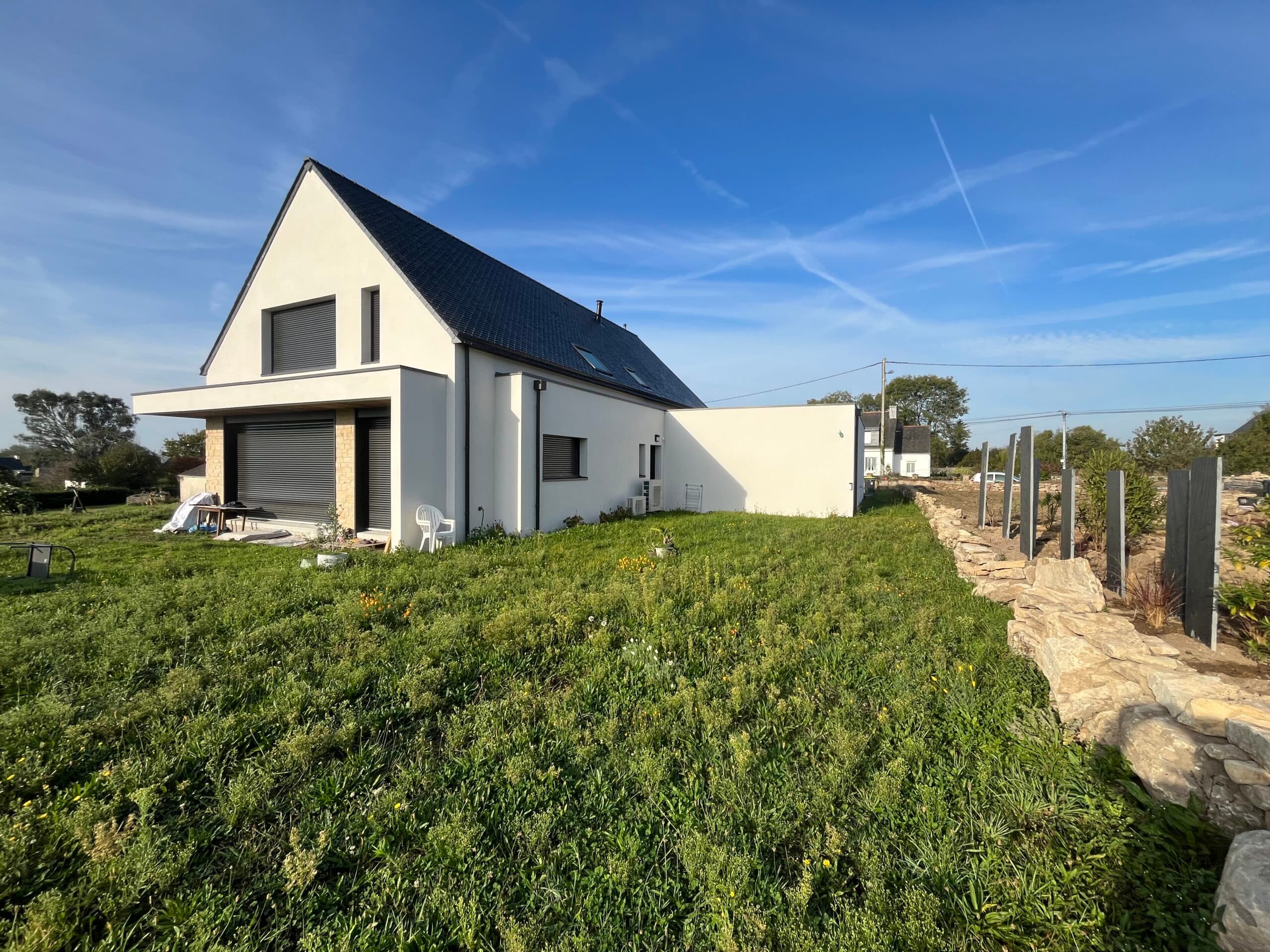Maison contemporaine en L construite par AJY Maçonnerie avec toiture ardoise, bardage moderne et larges baies vitrées sur jardin.