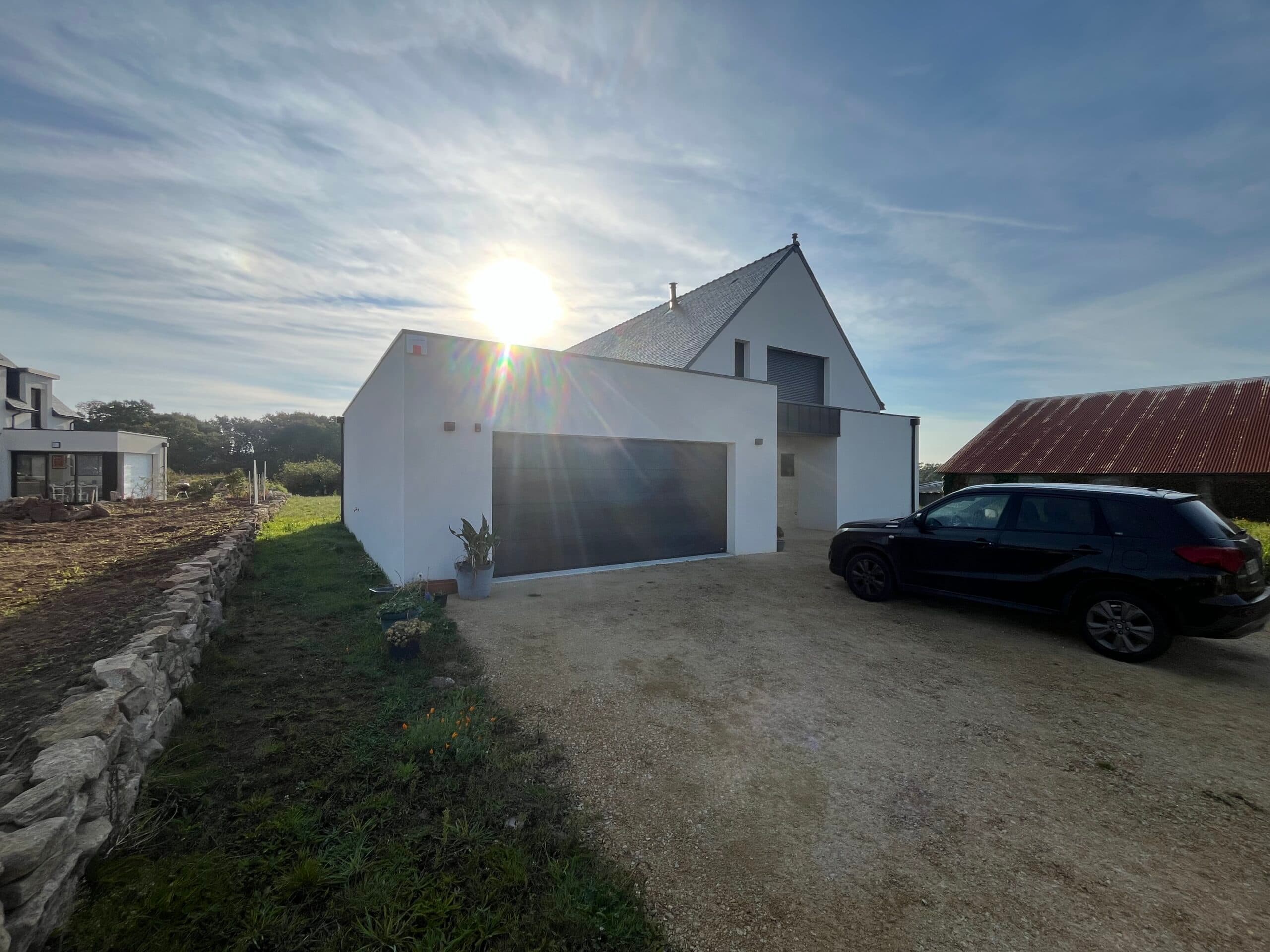 Façade avant de maison neuve avec garage accolé et cour en gravier, chantier de construction AJY Maçonnerie en campagne bretonne