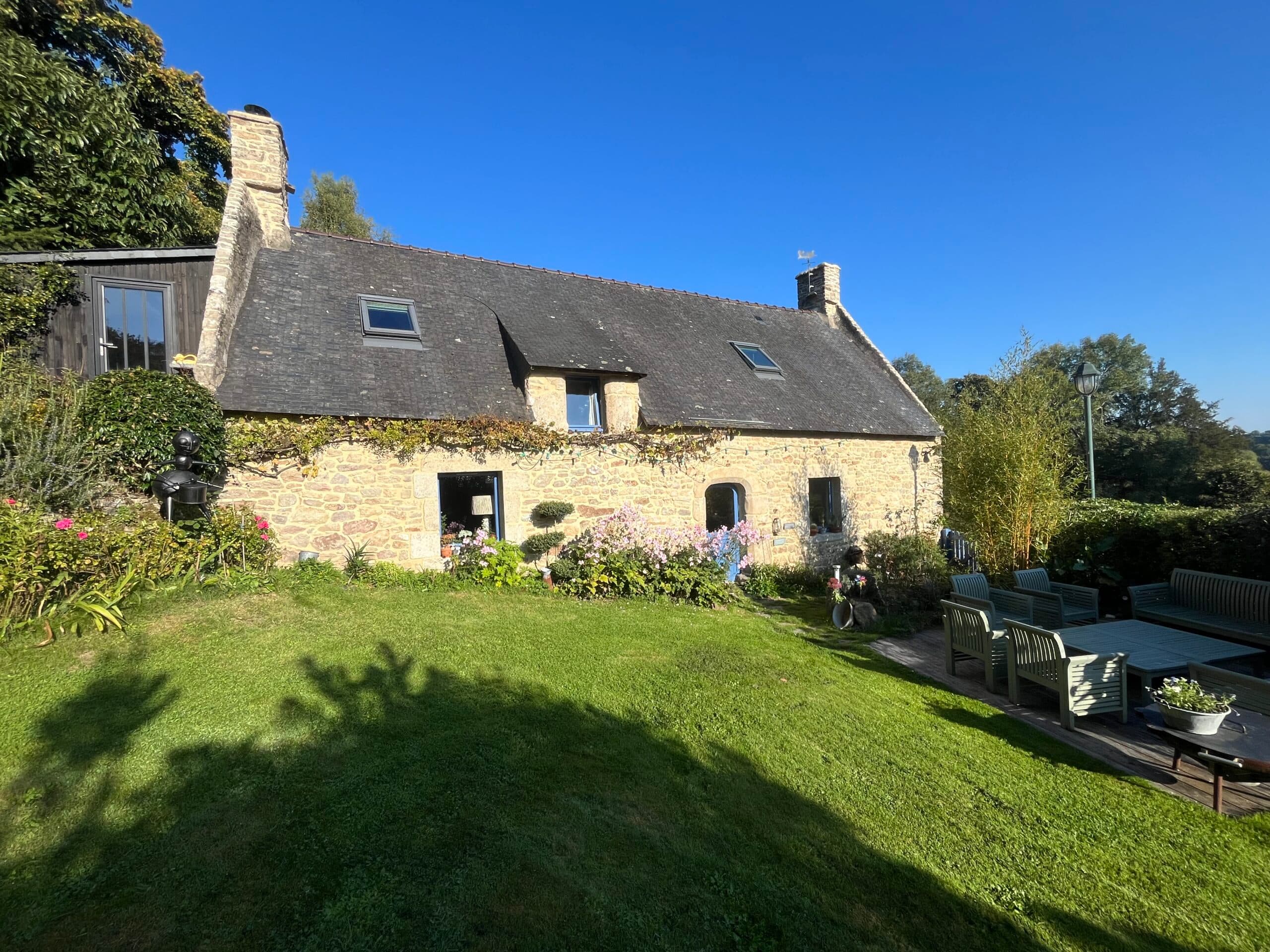 Maison en pierre avec portail bleu et joints de maçonnerie mis en valeur par la lumière naturelle.